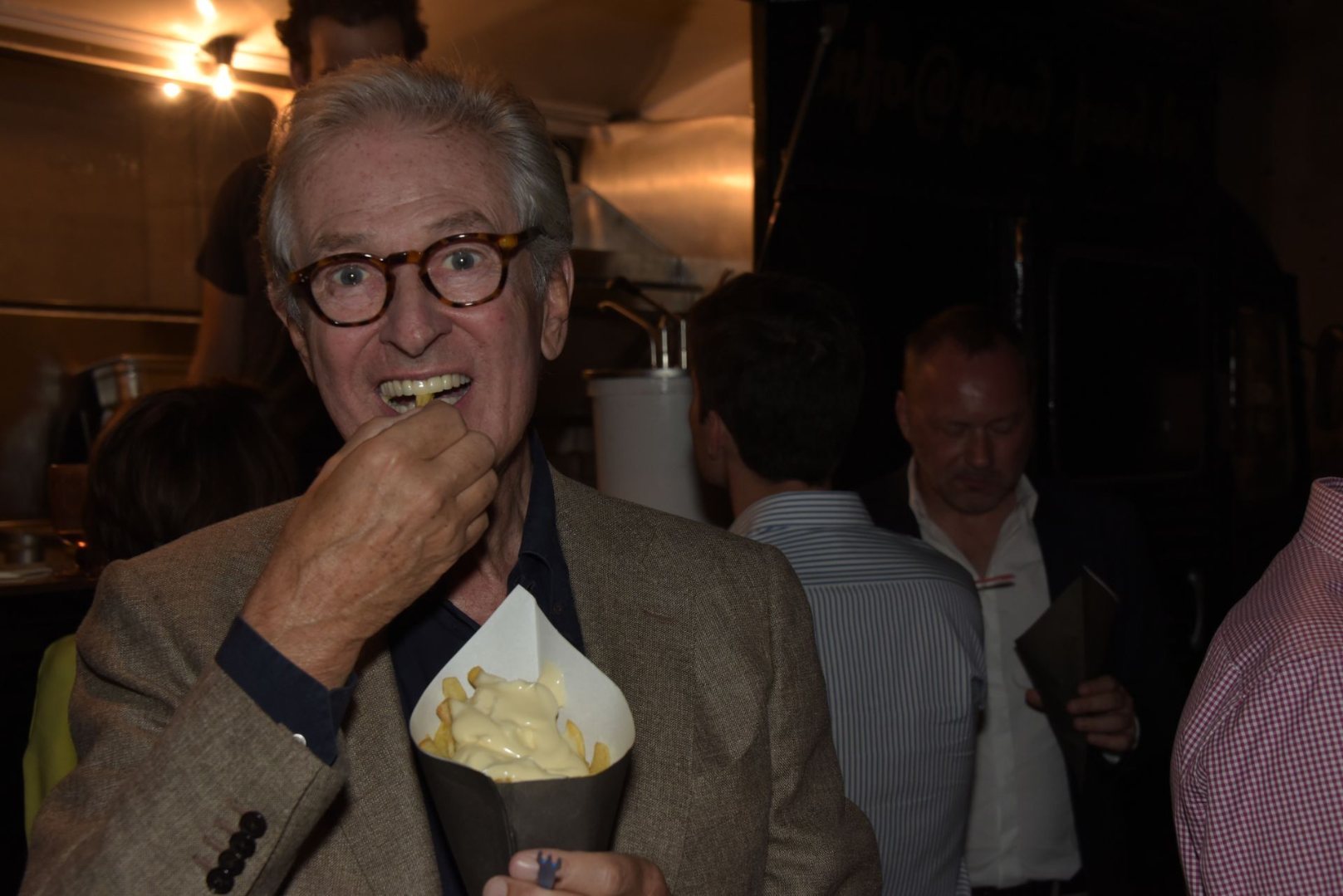 mensen eten frietjes vanuit foodtruck op een feest